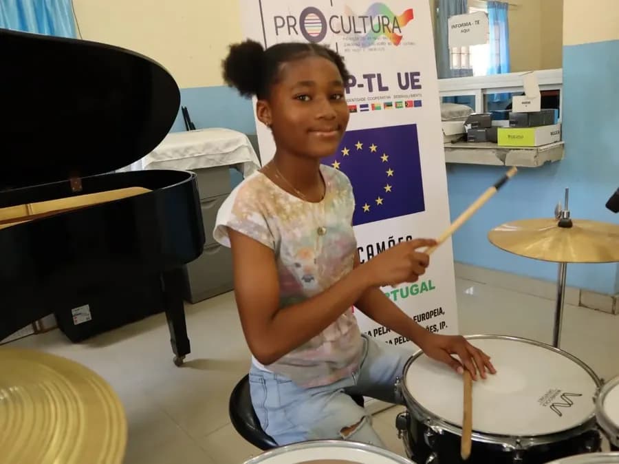 Una studentessa alla batteria della Casa da Música di Benguela, davanti al banner del programma europeo PROCULTURA
